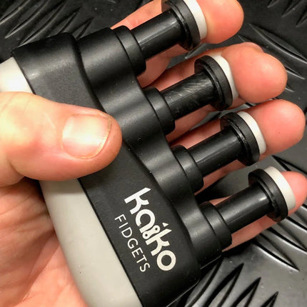 Hand holding a black and gray Hand & Finger Grip Exerciser & Fidgeting Sensory Tool designed for finger strength and sensory stimulation.