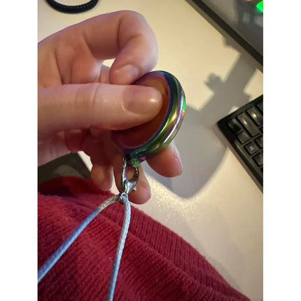 Hand holding Groove Stone - Dual Support Necklace & Key Chain sensory toy near computer keyboard on desk