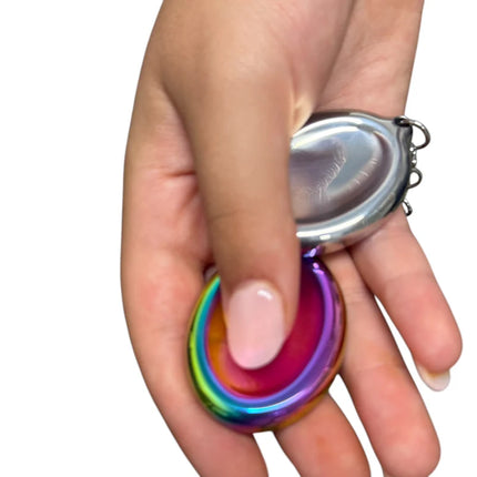 Hand holding a colorful metallic fidget tool with a silver backing, Groove Stone - Dual Support Necklace & Key Chain
