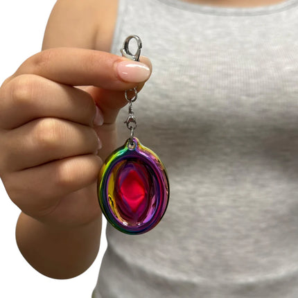 Hand holding Groove Stone - Dual Support Necklace & Key Chain with vibrant, colorful sensory fidget accessory against grey top background