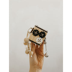 Hand holding Busy Cube sensory toy with gears, beads, and a bell, helping families thrive with tools to calm and connect