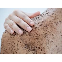 Close-up of a hand applying Coffee Body Scrub Original Warm Vanilla Blend on shoulder to soothe and exfoliate skin.