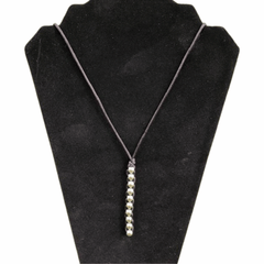 Caterpillar Unisex Necklace with silver bead detail on a simple black cord displayed on a black velvet stand