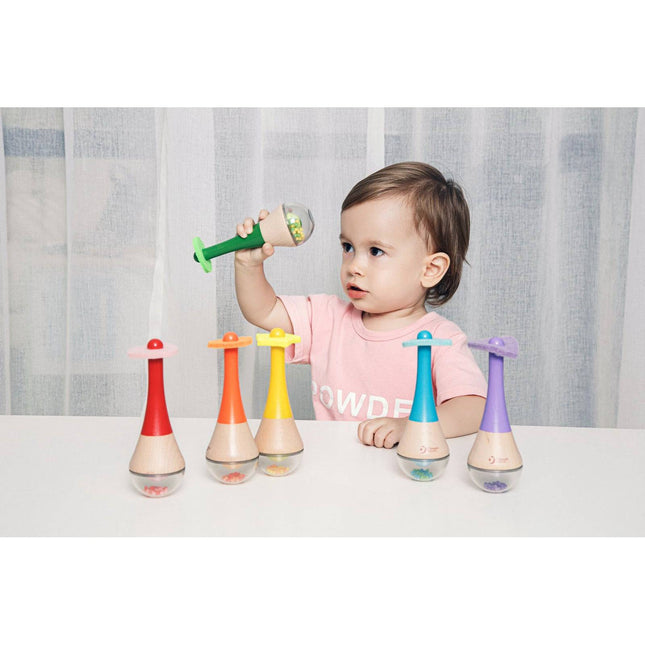 Child playing with Rainbow Maracas colorful sensory musical instruments on white table.