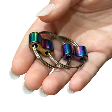 Hand holding two metallic iridescent Luxe Loop sensory fidget rings with smooth rounded edges.