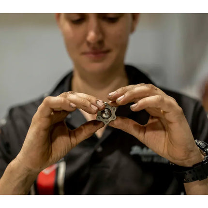 Person holding and examining a small metallic sensory toy called Magic Ball Fidget by Kaiko with focused attention