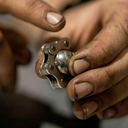 Close-up of hands holding a metal sensory toy called Magic Ball Fidget by Kaiko, designed for stress relief and focus.