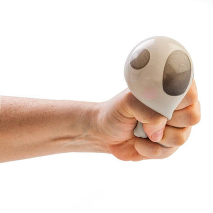 Hand squeezing a soft, beige pug-shaped fidget toy from Smoosho's Pets, helping families thrive with calm.