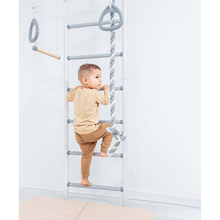 Child climbing a gray and white Sensory Swedish Climbing Frame - No Drill with rope and rings in a bright room