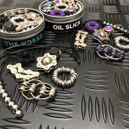 The Works Fidget Kit with assorted metal and colorful tactile sensory tools on a textured surface
