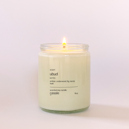 Lit UBUD SINGLE WICKED SOY CANDLE (8oz / 226g) in clear jar with calming amber and cedarwood scent Helping families thrive