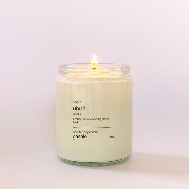 Lit UBUD SINGLE WICKED SOY CANDLE (8oz / 226g) in clear jar with calming amber and cedarwood scent Helping families thrive