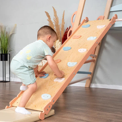 Child climbing on a wooden climbing ramp attached to the Wooden Teepee Playground indoor playset